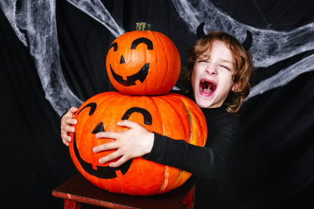 A young boy in halloween costume with pumpkins having funの写真素材