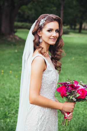 Beautiful bride outdoors in a park . Bridal style