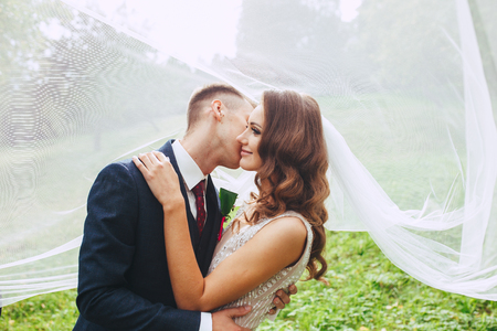 close up romantic portrait of beautiful wedding couple under the veil .の写真素材