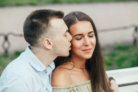 Happy young couple in love sitting on a park bench and huggingの写真素材