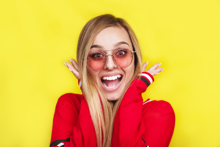 Surprised young woman in sunglasses over yellow backgroundの写真素材