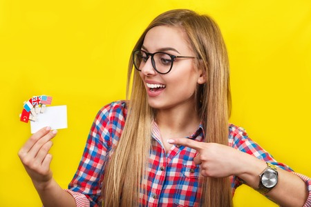 Young woman with card and flags of different speaking countries. Studio portrait of young beautiful female studentの写真素材