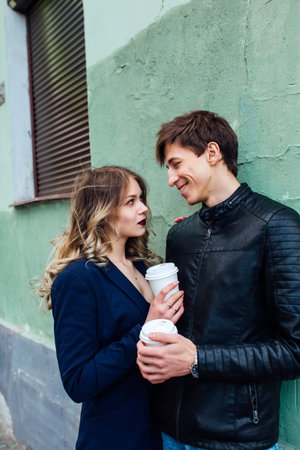 Portrait of a happy romantic couple with coffee walking outdoors in old european cityの写真素材
