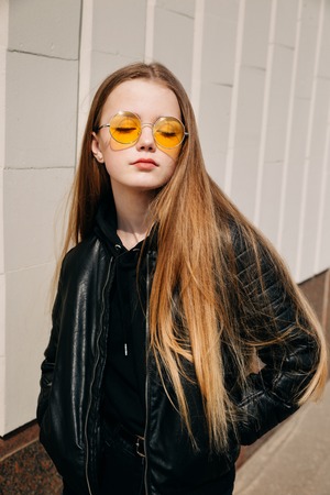beautiful fashionable kid girl with long hair in yellow sunglasses in city, Street fashion kid,の写真素材