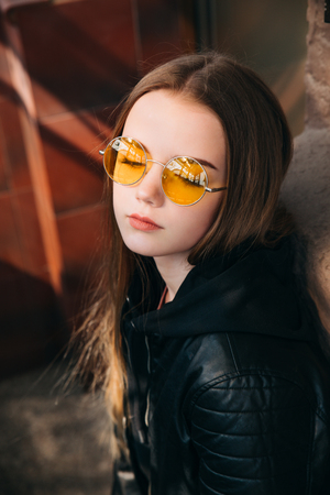 beautiful fashionable teenager girl with long hair in yellow sunglasses in city, Street fashion kid,の写真素材