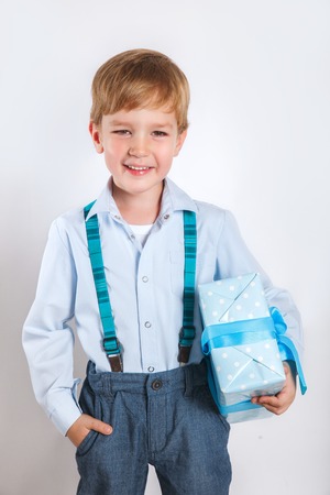 Portrait of a happy cute little kid holding gift box and looking at cameraの写真素材