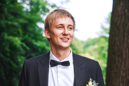 groom at wedding tuxedo smiling and waiting for bride. Rich groom at wedding day. Elegant groom in costume and bow-tie.の写真素材