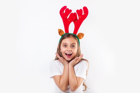 Smiling funny child in deer horns and white t-shirt making surprise and looking at camera .の写真素材