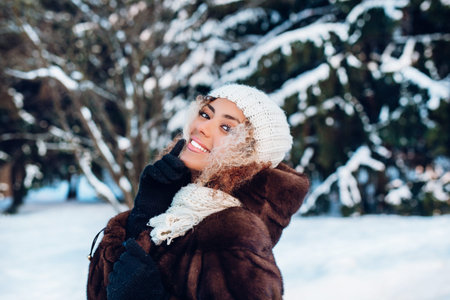 Happy winter moments of joyful young woman with afro hair, white winter clothes having fun on street...