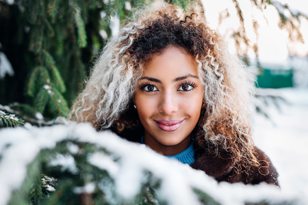 Close-up portrait of beautiful young afro american woman in winter forestの写真素材