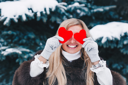 Portrait of a beautifull smiling woman in the forest holding red Valentines heart in the hands. Valentines Day. Valentines Day concept.の写真素材