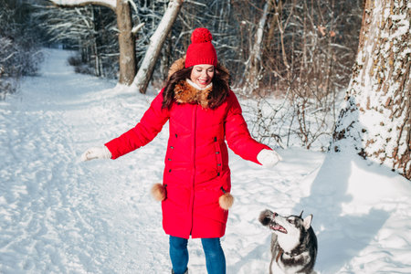 Young woman playing with her Husky dog in winter parkの写真素材