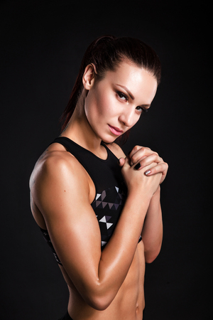 Strong woman bodybuilder with perfect abs, shoulders, biceps, triceps and chest. Photo of sporty young woman on black background.の写真素材