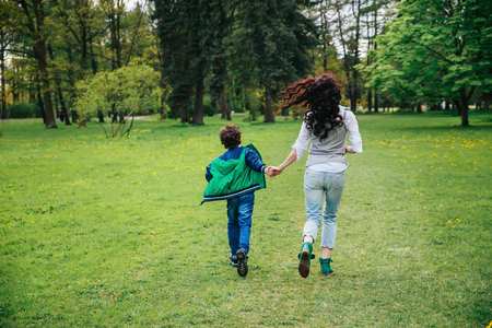 Young mother running with little boy on sunny day in the park.の写真素材