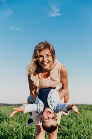 Happy woman with child playing together in fieldの写真素材