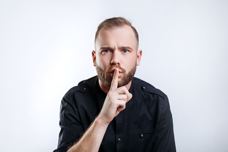 Portrait of stylish man with beard show sign silenceの写真素材