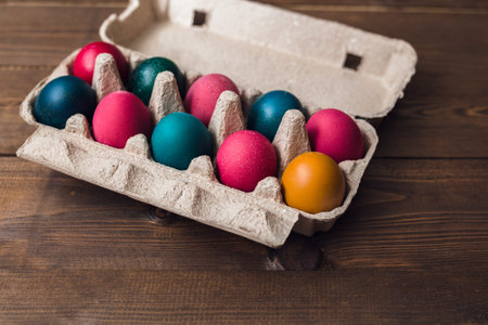 Top view of colorful Easter eggs in tray on brown wooden table background
