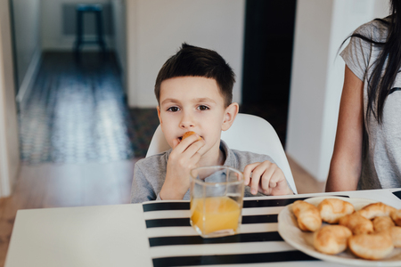 Beautiful young woman at home with her little cute son are having breakfast.の写真素材