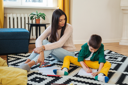 Young mother and her little son drawing together at home. Mixed race familyの写真素材