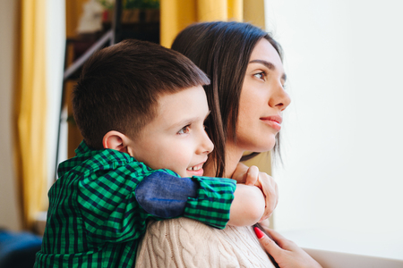 mother with son, happy family smiling and hugging at homeの写真素材