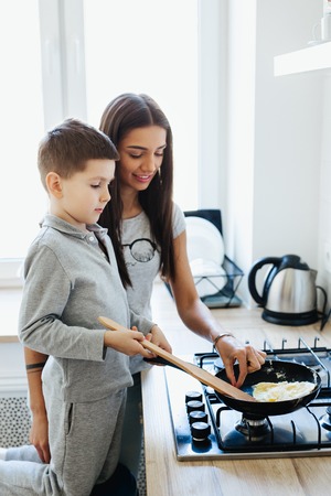 happy family in the kitchen. mother and child son preparing omeletの写真素材