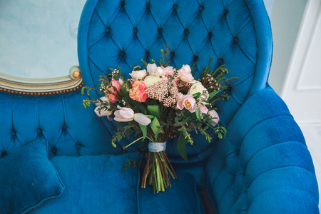 Rustic wedding bouquet with pink tulips, peonies, and greens on a blue sofa.の写真素材