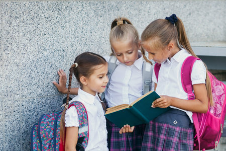 Portrait of smiling school kids standing in school terrace and reading book