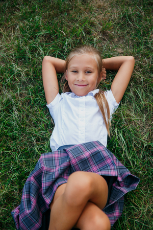Back to school. cute girl from elementary school lying at the school yard.の写真素材