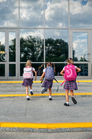 Group of elementary school girls running at school, back viewの写真素材