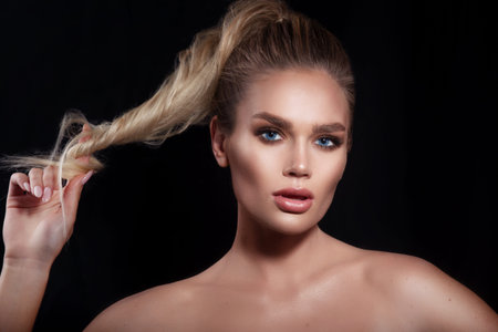 Beautiful sensual woman with blonde hair and professional make up on black backgroundの写真素材