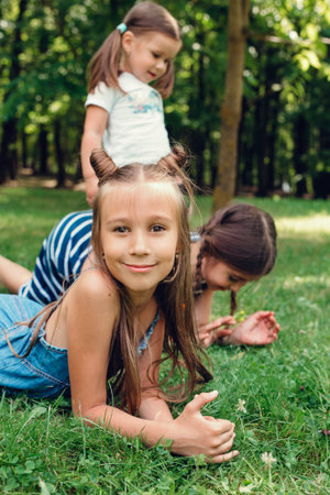 Three funny littlle girls playing on the grass in summer park