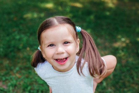 Portrait of funny beautiful little girl in the summer on the blur green background