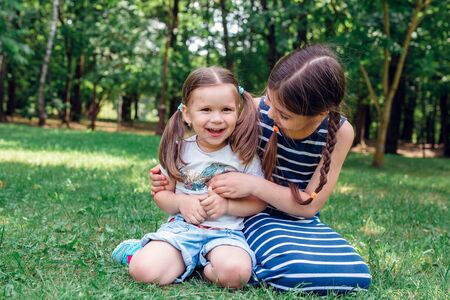 Two cute little sisters having fun in park in sunny summer dayの写真素材