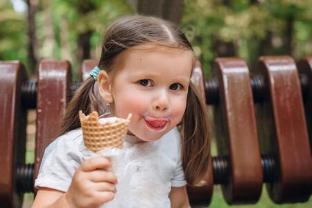 Cute toddler girl eating ice-cream in park in summer dayの写真素材