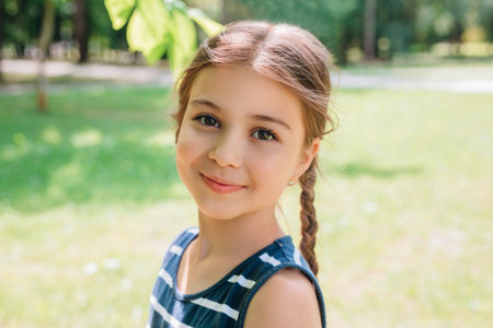 Portrait of adorable smiling little girl child with pigtails outdoor in summer day