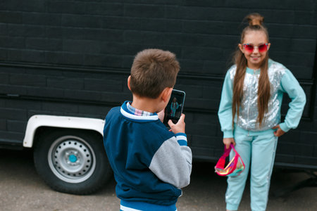 kid photographer with a mobile phone taking pictures of the girl