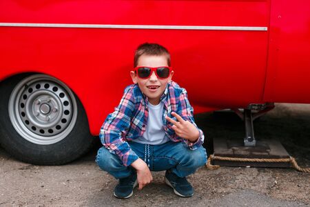 Fashion kid sin the city sitting on a red wall.の写真素材