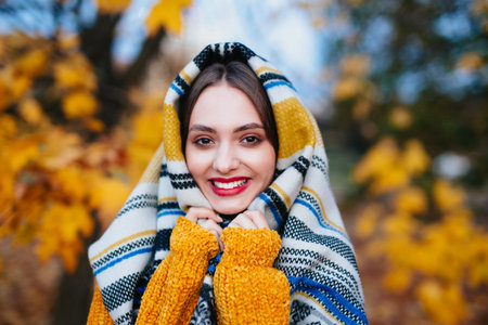 Funny girl with red lips in a warm plaid on a sunny autumn day
