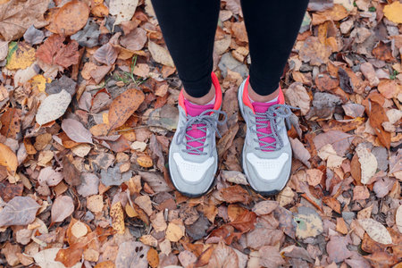 Close-up of feet of a runner running in autumn leaves in park