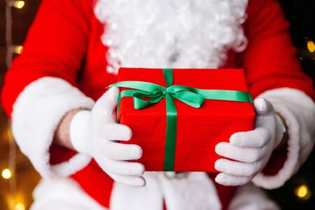 Red gift in Santa Claus hands near Christmas backgroundの写真素材