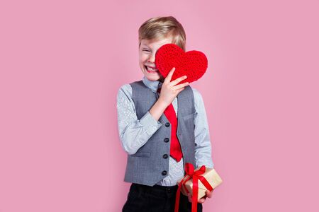 Charming little boy posing with heart on pink backgroundの写真素材