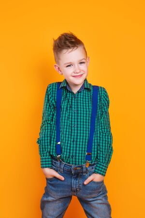 Beautiful smiling caucasian boy in a green shirt on yellow background.の写真素材