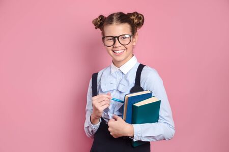 Cheerful student in glasses hugging books on pink studio backgroundの写真素材