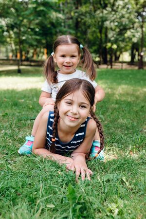 happy children playing and lying on green grass outdoors in summer parkの写真素材