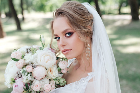 Beautiful bride with wedding flowers bouque in park. Bride with wedding makeup and hairstyle.