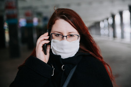 Young woman with face mask talking on the phone in city