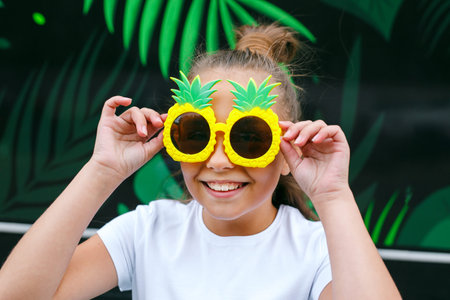 funny little girl with glasses pineapple smiling city streetの写真素材