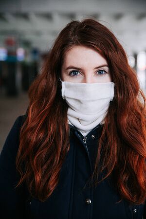 Corona virus pandemic. Beautiful red haired girl with medical mask.の写真素材