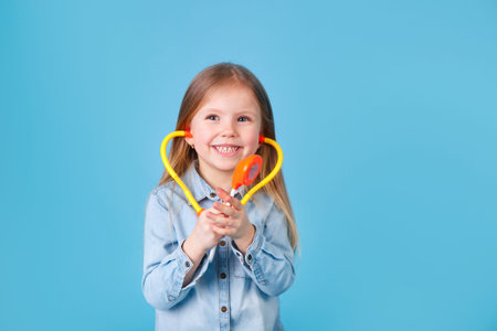 Portrait of a cute little girl with stethoscope on blue studio background