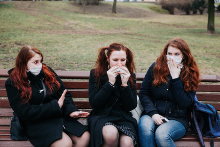 Woman suffer from sick and wearing face mask. European woman in protective mask feeling bad in parkの写真素材
